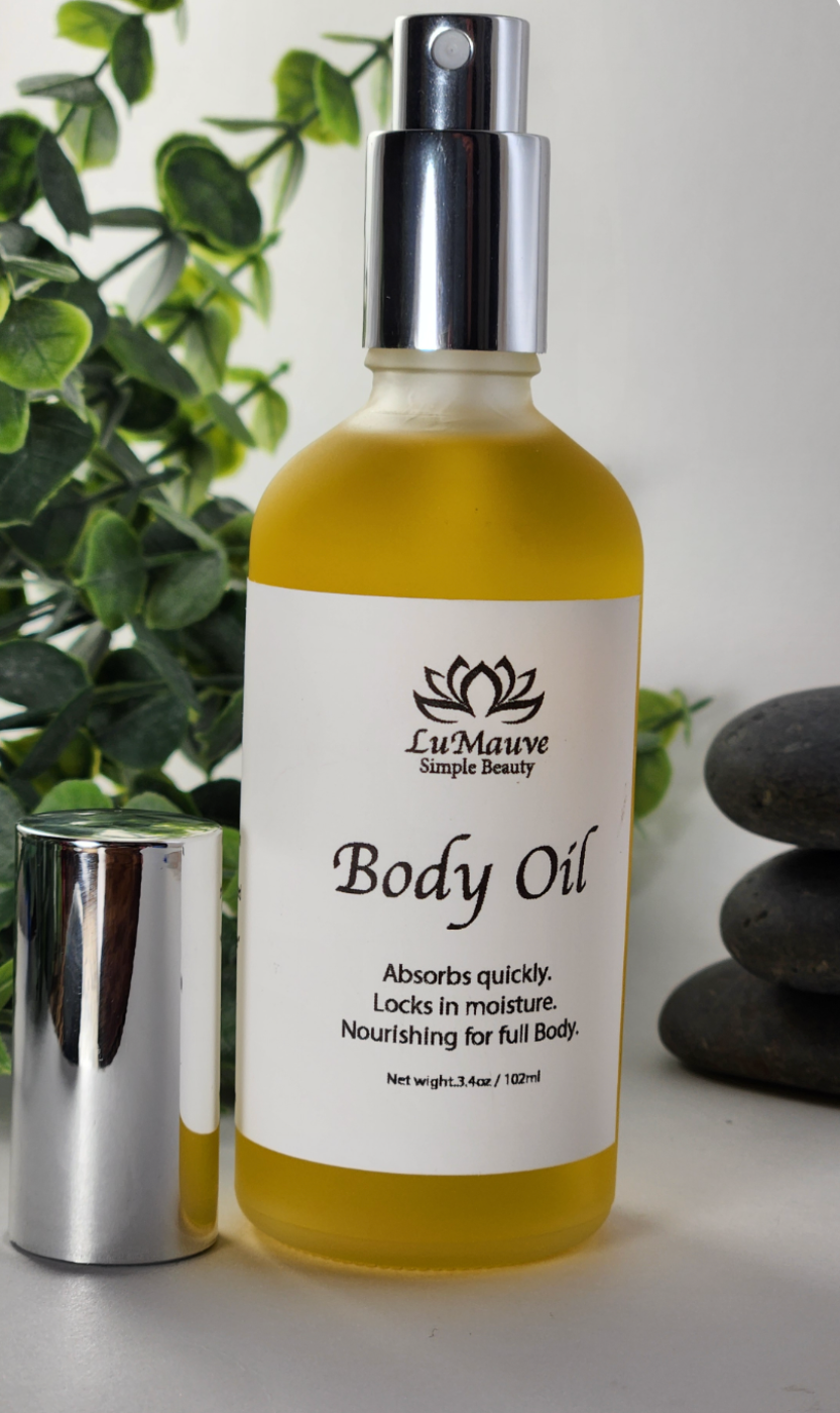 Body oil bottle with a white label on a light background with greenery and stones.