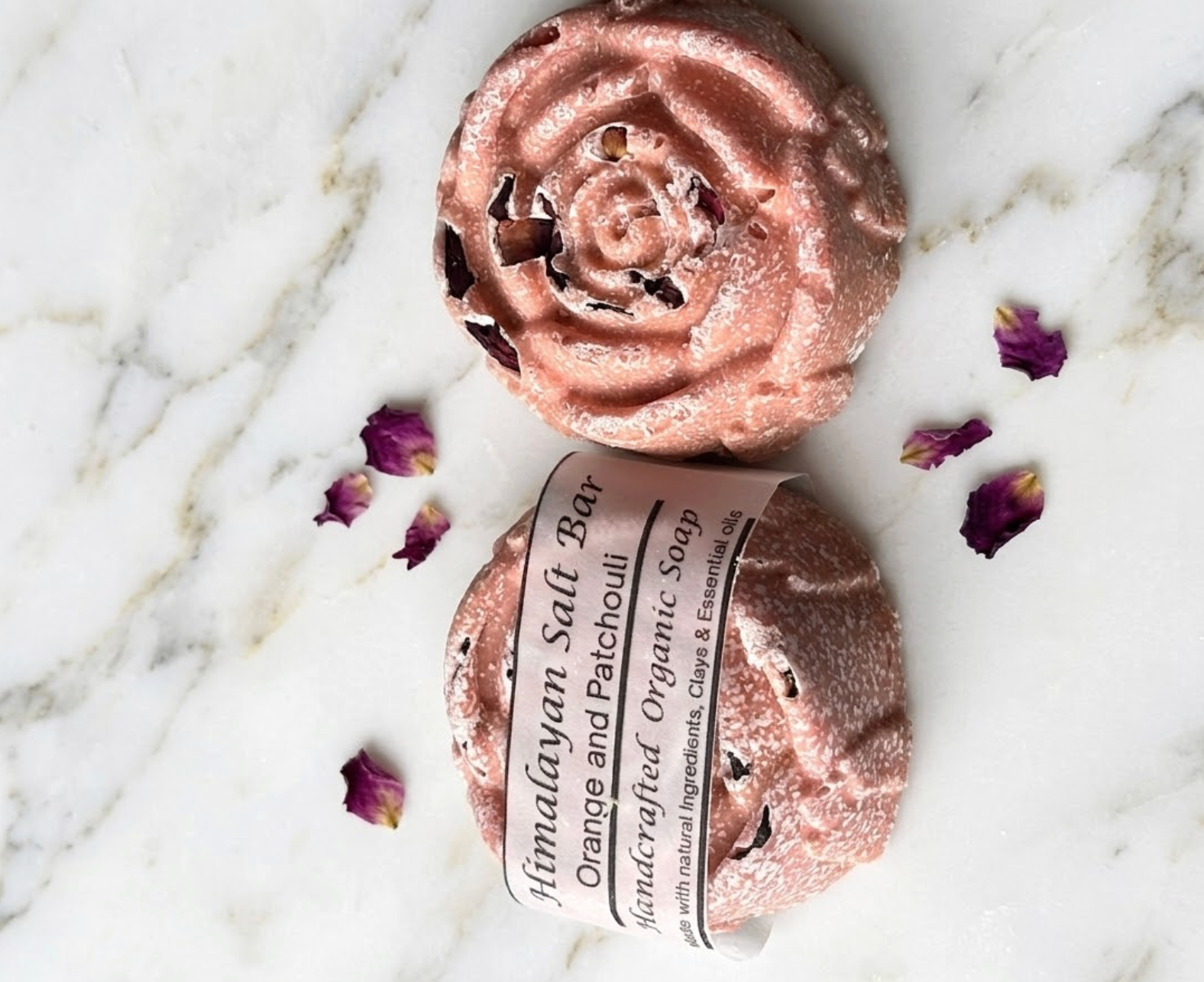 Himalayan salt bar with rose gold packaging on a marble surface with dried flowers.