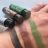 Three face paint tubes with swatches on a wrist