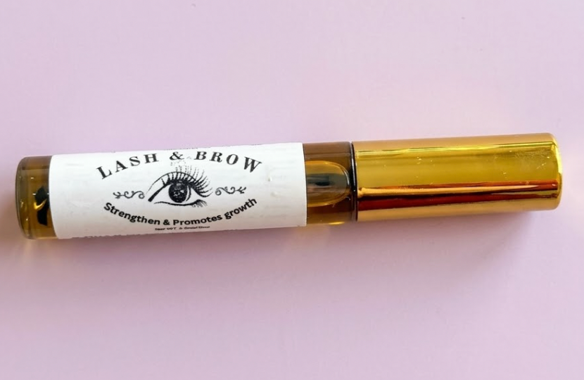Lash container with gold cap and white label on a light pink background