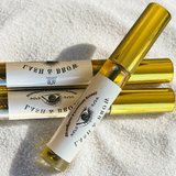 Three gold lash bottles with labels on a textured white surface