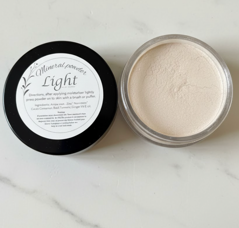 Open container of mineral powder with black lid on a marble surface