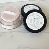 Two containers of mineral powder labeled 'Light' on a marble surface.