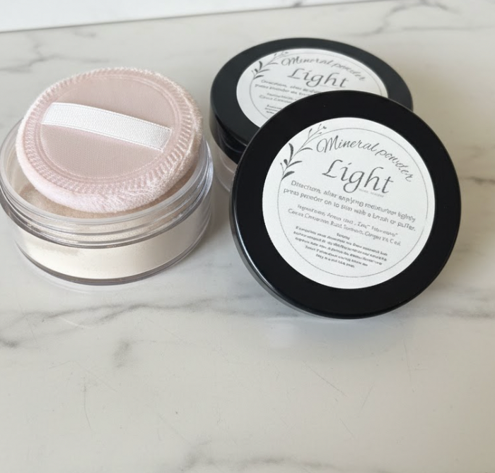 Two containers of mineral powder labeled 'Light' on a marble surface.